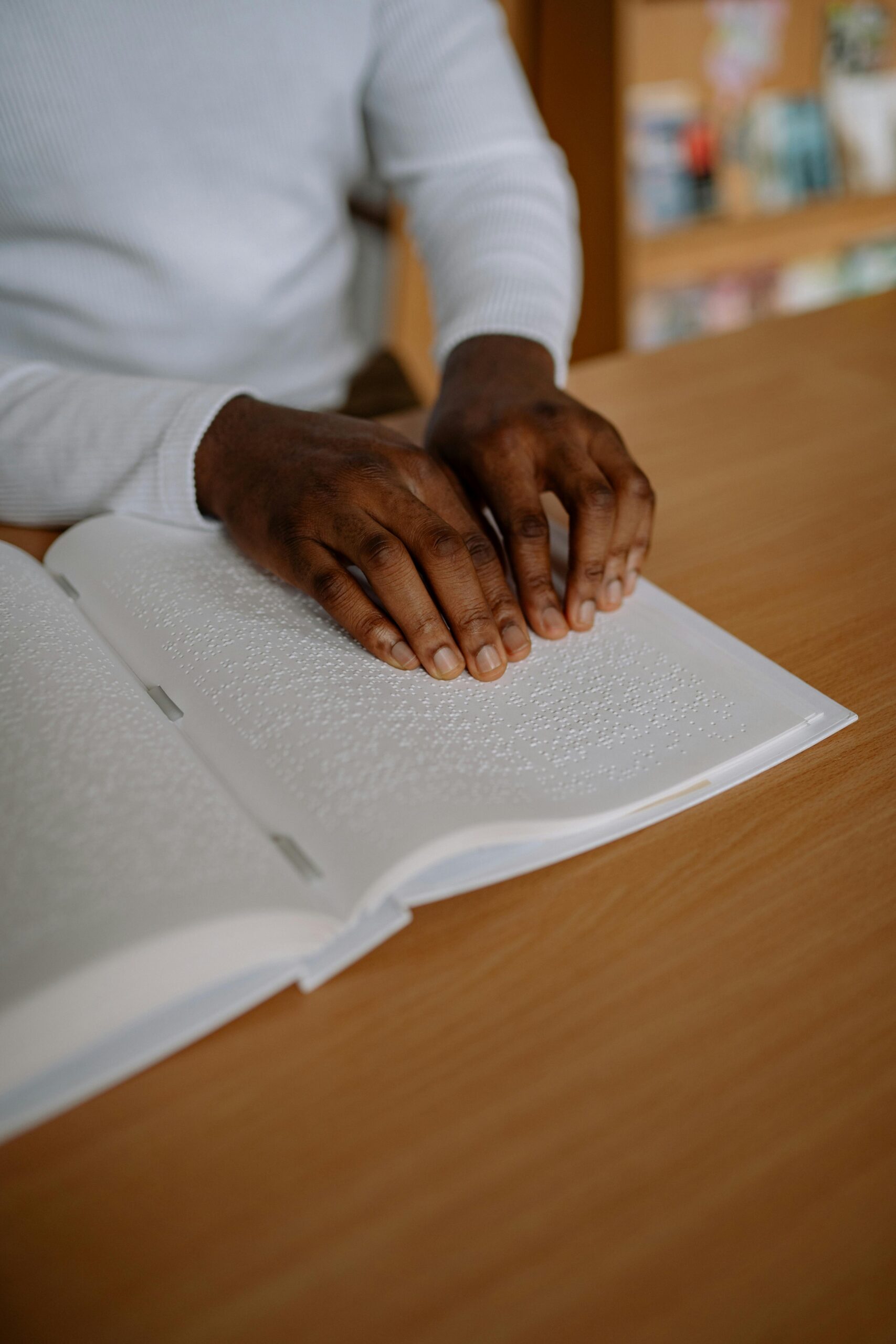Close-up image showing hands reading a book in Braille. Represents accessibility and visual impairment support.